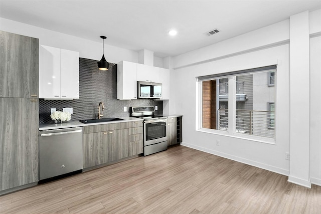 kitchen with pendant lighting, white cabinetry, stainless steel appliances, and backsplash