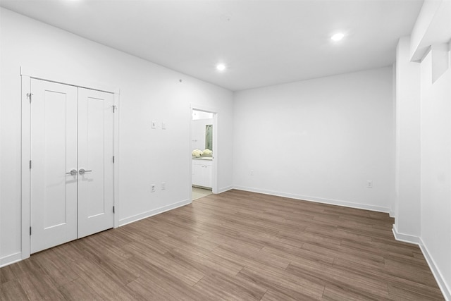 unfurnished bedroom with ensuite bath and light hardwood / wood-style floors