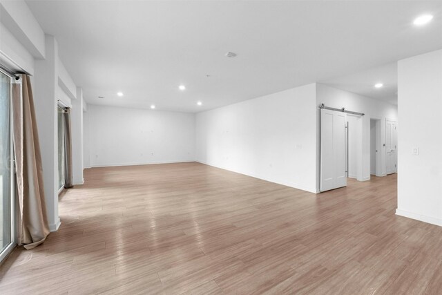 unfurnished room with a barn door and light hardwood / wood-style floors