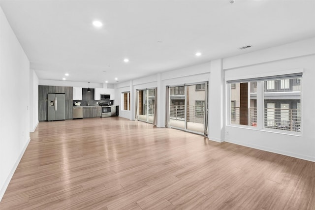 unfurnished living room with sink and light hardwood / wood-style flooring