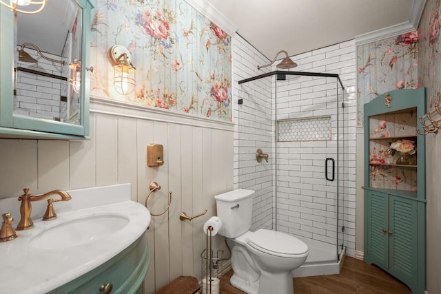 bathroom with hardwood / wood-style flooring, vanity, ornamental molding, a shower with shower door, and toilet