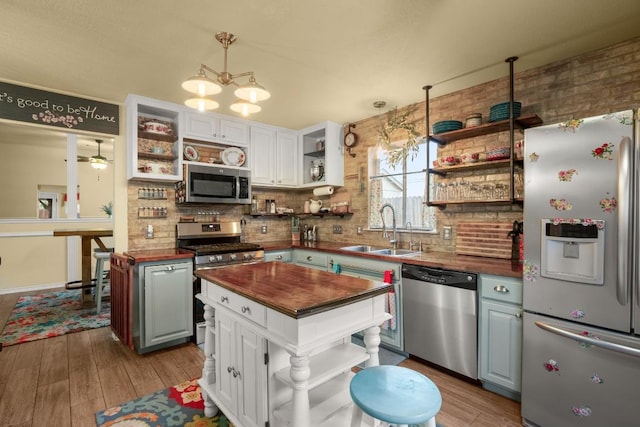 kitchen featuring sink, white cabinetry, stainless steel appliances, a center island, and wood counters