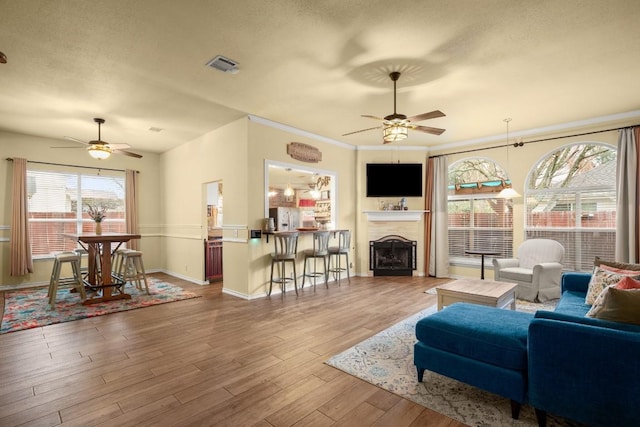 living room featuring hardwood / wood-style floors, a textured ceiling, ornamental molding, and ceiling fan