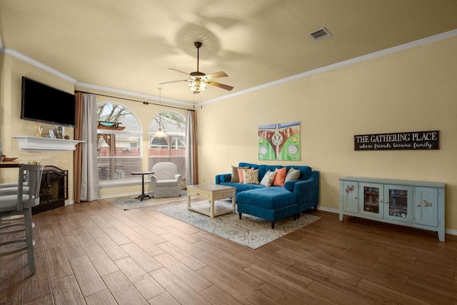 living room with hardwood / wood-style floors, ornamental molding, and ceiling fan