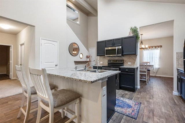 kitchen with pendant lighting, a kitchen island with sink, sink, and dark wood-type flooring