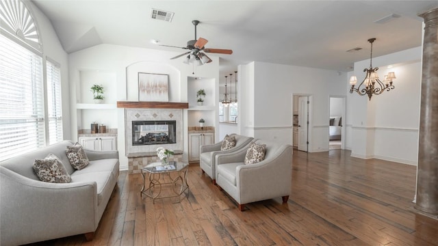 living room featuring lofted ceiling, ceiling fan with notable chandelier, a tile fireplace, and dark hardwood / wood-style floors