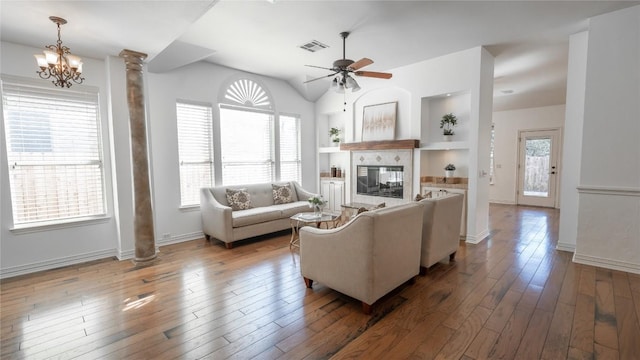 living room featuring a tiled fireplace, hardwood / wood-style flooring, decorative columns, and a healthy amount of sunlight