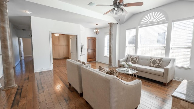 living room featuring hardwood / wood-style flooring, a wealth of natural light, ceiling fan with notable chandelier, and ornate columns