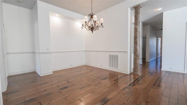 unfurnished dining area with decorative columns, dark hardwood / wood-style floors, and a notable chandelier