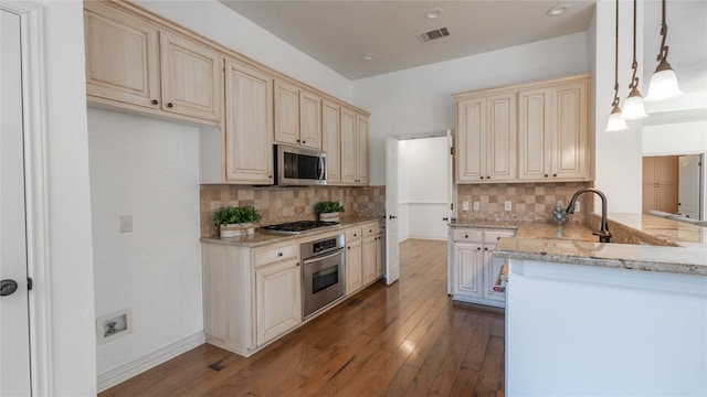 kitchen with hanging light fixtures, appliances with stainless steel finishes, dark hardwood / wood-style flooring, kitchen peninsula, and light stone countertops