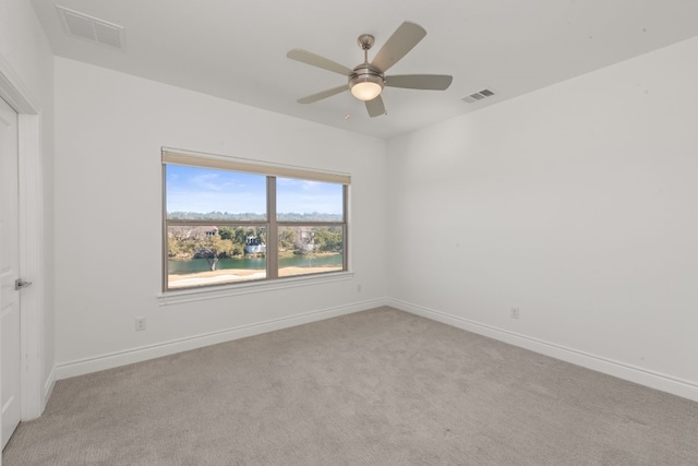 carpeted spare room featuring a water view and ceiling fan