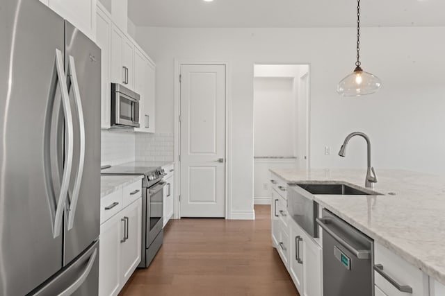 kitchen featuring white cabinetry, pendant lighting, light stone countertops, and appliances with stainless steel finishes