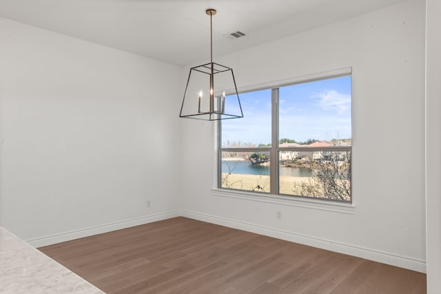 unfurnished dining area with a water view, a chandelier, and dark hardwood / wood-style flooring