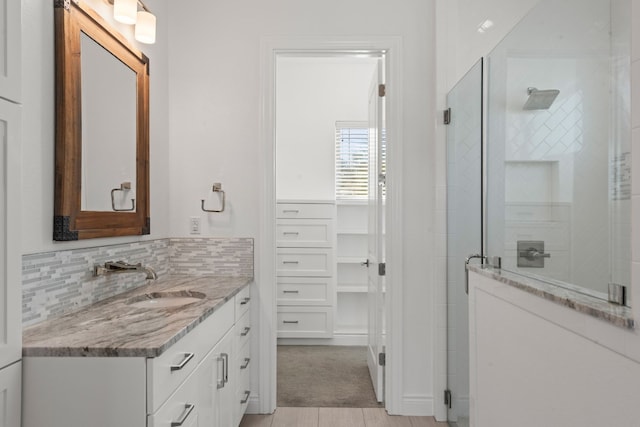 bathroom featuring tasteful backsplash, vanity, and a shower with shower door