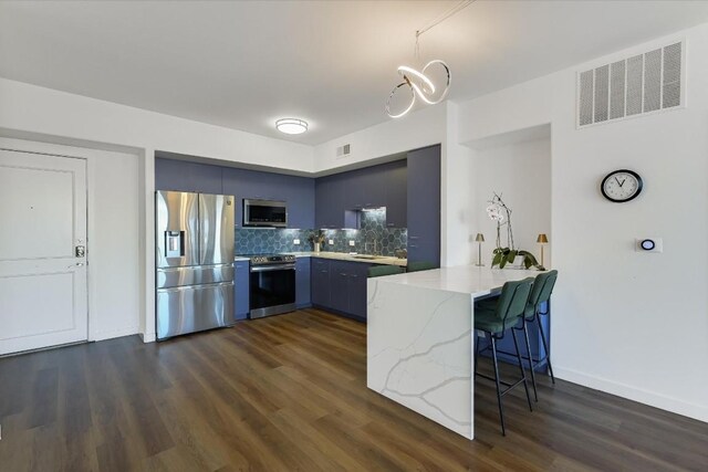 kitchen featuring dark hardwood / wood-style floors, a kitchen breakfast bar, kitchen peninsula, and appliances with stainless steel finishes