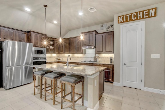 kitchen featuring sink, decorative backsplash, a kitchen island with sink, light stone counters, and stainless steel appliances