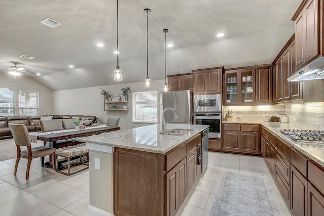 kitchen with vaulted ceiling, pendant lighting, sink, stainless steel appliances, and a center island with sink