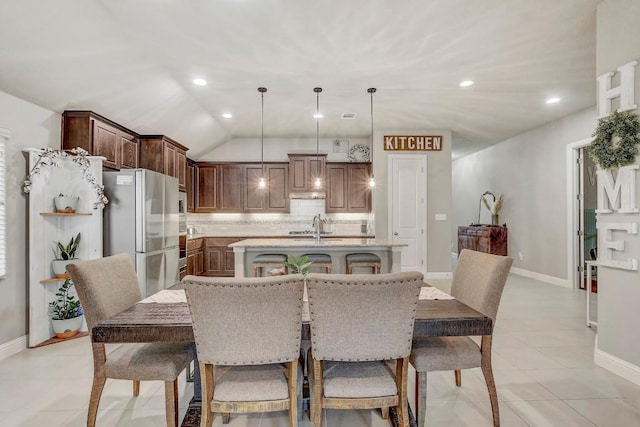 tiled dining area with lofted ceiling and sink