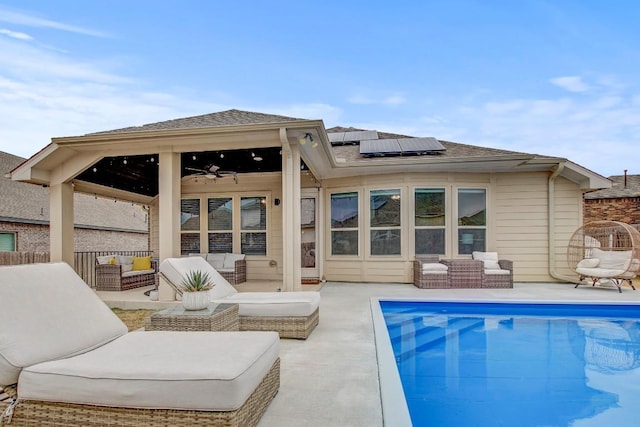 rear view of property with ceiling fan, outdoor lounge area, a patio area, and solar panels