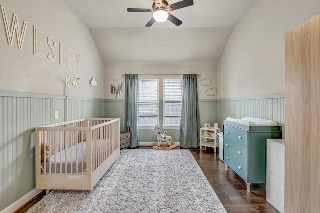 bedroom featuring a nursery area, ceiling fan, lofted ceiling, and dark hardwood / wood-style floors