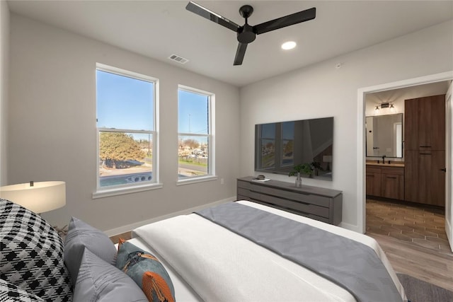 bedroom with ceiling fan, ensuite bath, wood-type flooring, and sink