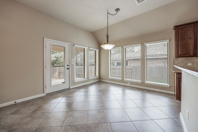 unfurnished dining area with lofted ceiling, a healthy amount of sunlight, and light tile patterned floors