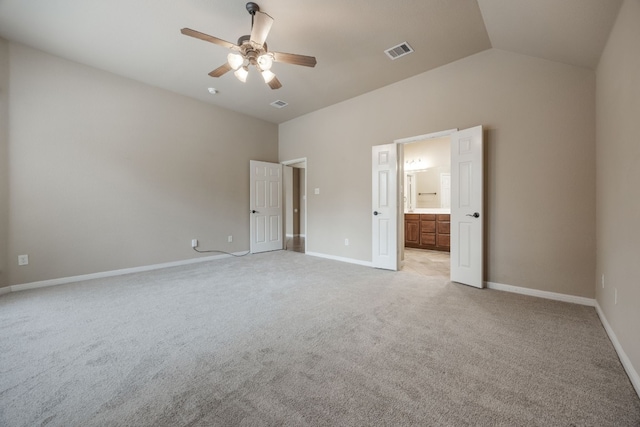 unfurnished bedroom featuring light carpet, ensuite bath, vaulted ceiling, and ceiling fan