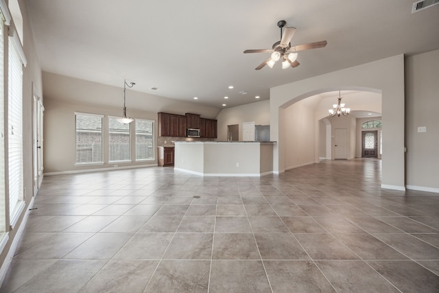 unfurnished living room with ceiling fan with notable chandelier and light tile patterned floors