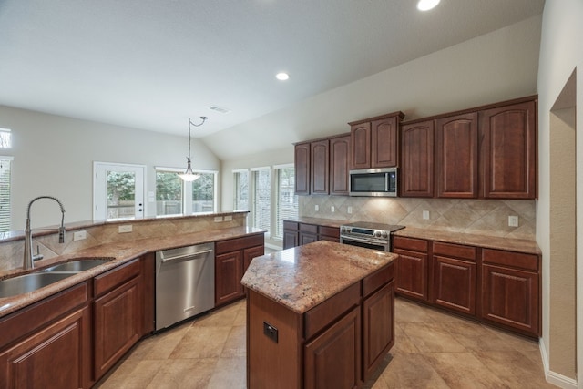 kitchen featuring sink, decorative light fixtures, appliances with stainless steel finishes, a kitchen island, and backsplash