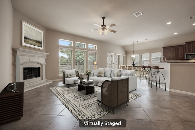 tiled living room featuring ceiling fan, lofted ceiling, sink, and a fireplace