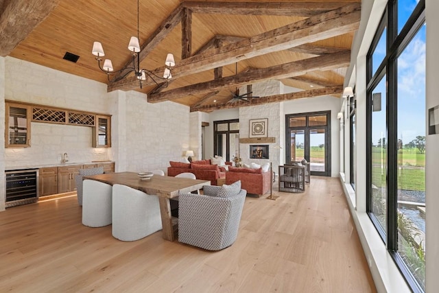 dining space with indoor wet bar, beverage cooler, light hardwood / wood-style flooring, and wooden ceiling