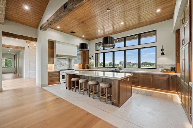 1318 Country Side Bnd, Fredericksburg, TX 78624 - kitchen featuring stainless steel range, wooden ceiling with exposed beams, a large island, decorative backsplash, and brown cabinetry