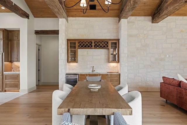 1318 Country Side Bnd, Fredericksburg, TX 78624 - dining space featuring wine cooler, bar with sink, light wood-style floors, wooden ceiling with exposed beams, and a chandelier