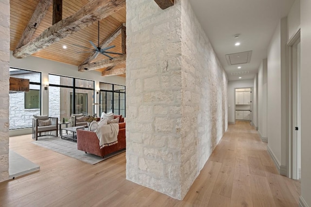 hall with beamed ceiling, a towering ceiling, light wood-type flooring, and wooden ceiling