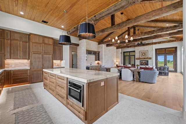 1318 Country Side Bnd, Fredericksburg, TX 78624 - kitchen featuring wood ceiling with exposed beams, a center island, open floor plan, light stone countertops, and decorative light fixtures