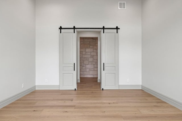 1318 Country Side Bnd, Fredericksburg, TX 78624 - unfurnished room featuring light wood finished floors, baseboards, and a barn door