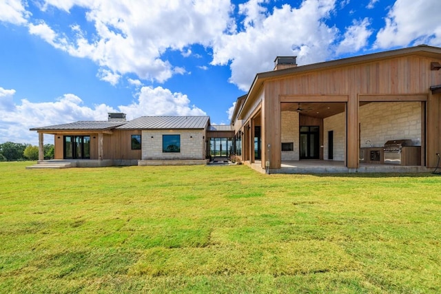 back of property featuring a patio, exterior kitchen, and a lawn