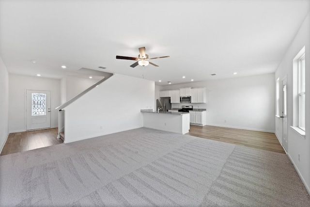 unfurnished living room featuring ceiling fan and light hardwood / wood-style floors