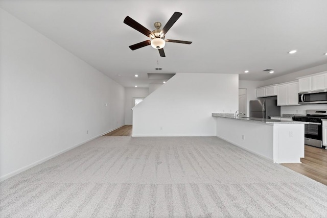 unfurnished living room featuring light colored carpet and ceiling fan