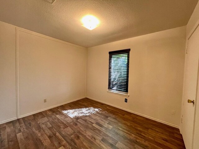 unfurnished room featuring dark wood-type flooring and a textured ceiling