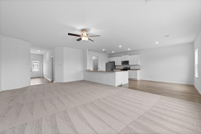 unfurnished living room featuring ceiling fan and light hardwood / wood-style flooring