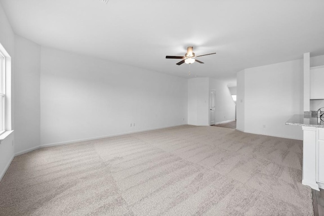 unfurnished living room with light colored carpet and ceiling fan