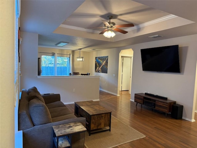 living room with a raised ceiling, crown molding, hardwood / wood-style floors, and ceiling fan