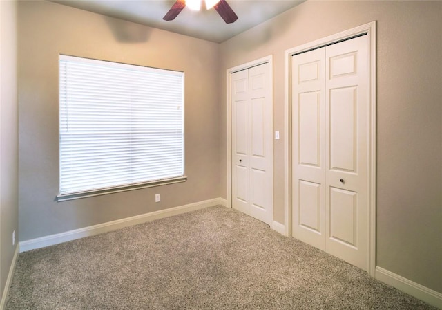 unfurnished bedroom featuring two closets, carpet floors, and ceiling fan