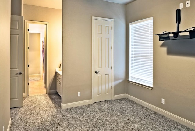 unfurnished bedroom featuring ensuite bath and carpet