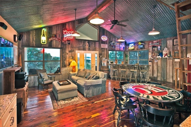 interior space featuring indoor bar, dark wood-type flooring, ceiling fan, high vaulted ceiling, and wood walls