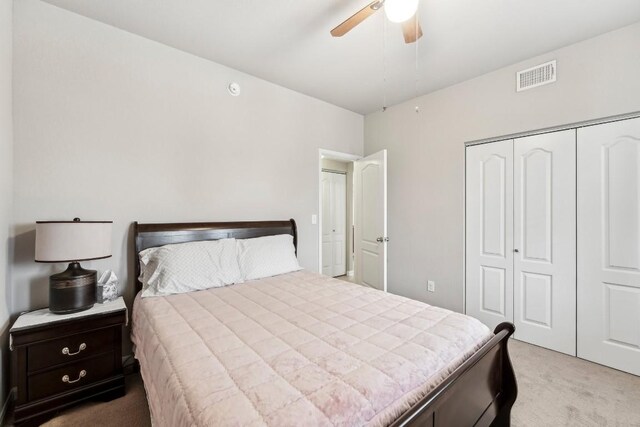 bedroom with light colored carpet, ceiling fan, and a closet