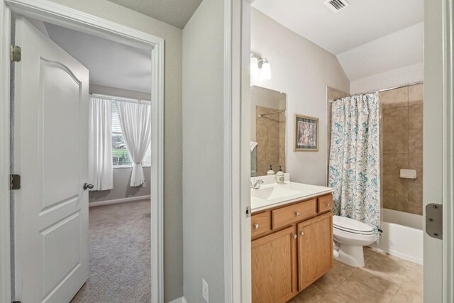 full bathroom featuring shower / bathtub combination with curtain, tile patterned flooring, vanity, vaulted ceiling, and toilet