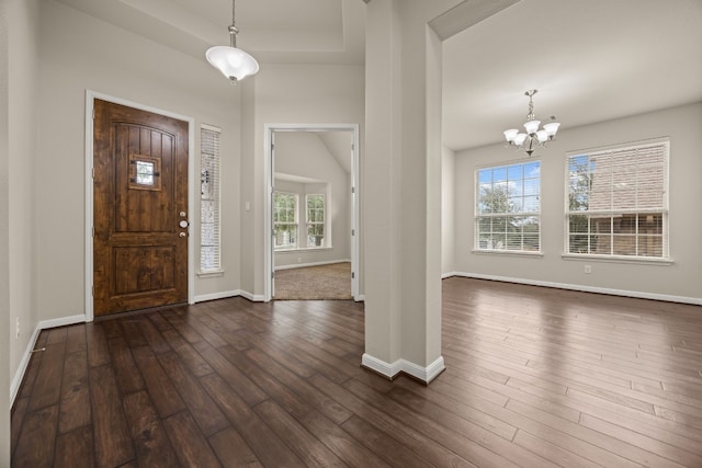 foyer featuring an inviting chandelier, a tray ceiling, and dark hardwood / wood-style floors