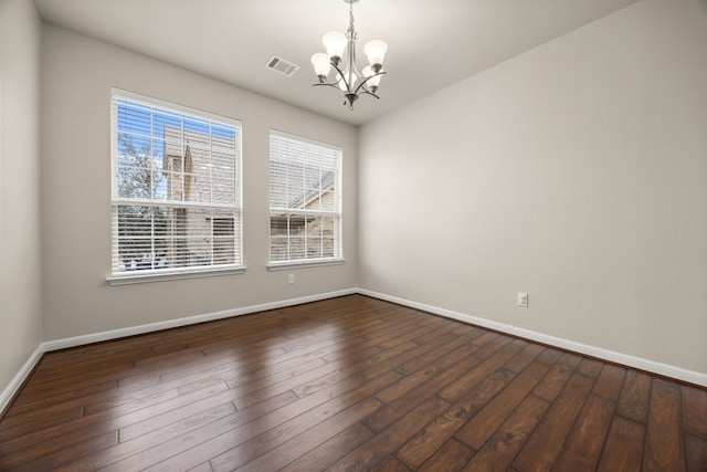 spare room with dark hardwood / wood-style floors and a chandelier